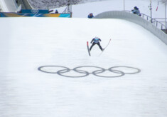 Ein Nordischer Kombinierer springt über die Olympischen Ringe.